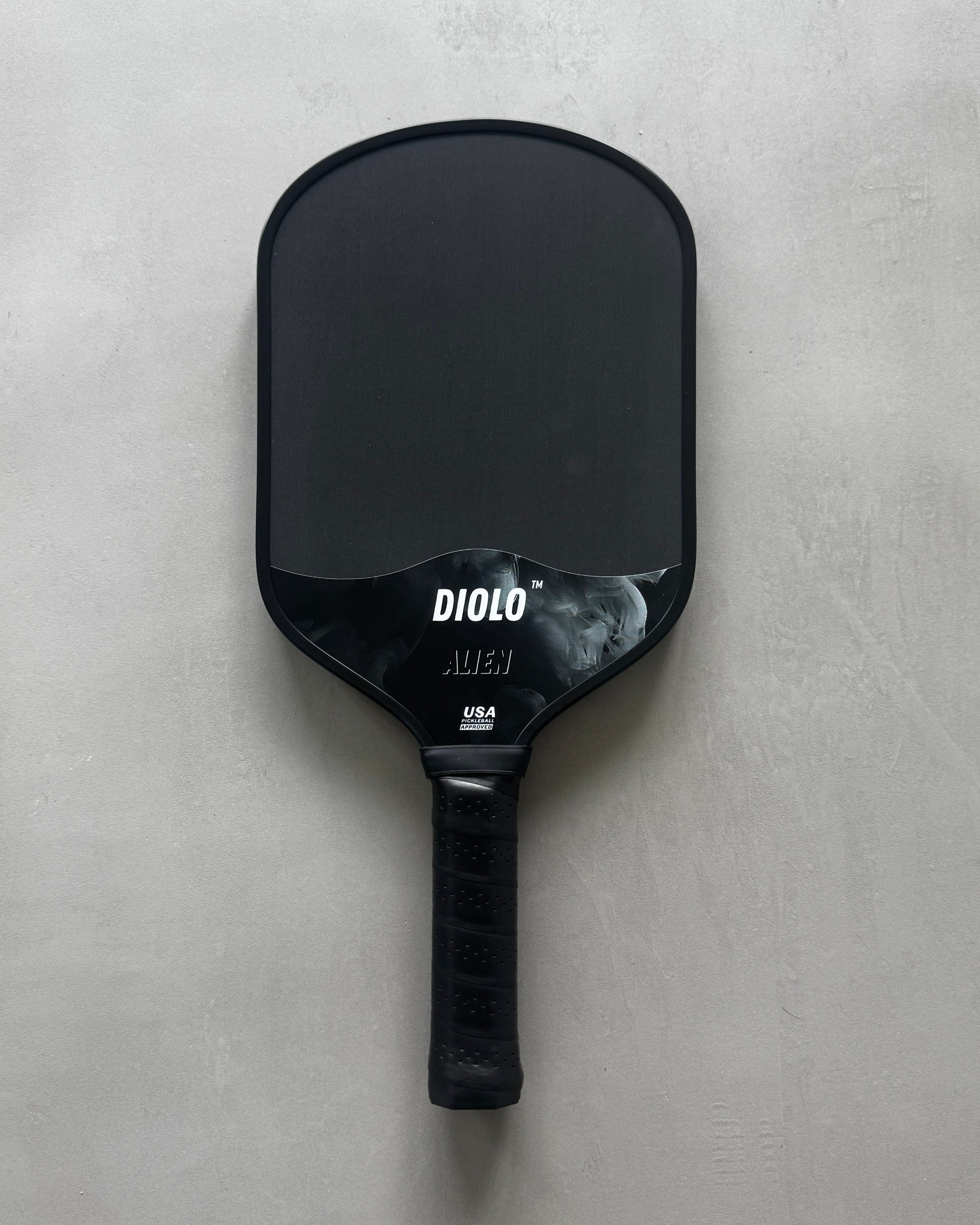 A black pickleball paddle with the brand name 'DIOLO' written on it, placed on a grey surface.
